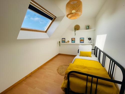 1 dormitorio con 1 cama con sábanas amarillas y ventana en Bord de mer, maison paisible et rénovée à Penvins, en Sarzeau