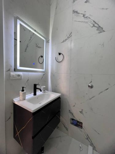 a white bathroom with a sink and a mirror at Cactus Apartments in Durrës