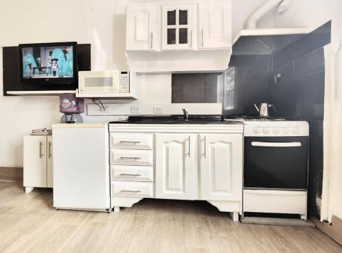 馬丁尼茲的住宿－Jazmines Apart，厨房配有白色橱柜和黑炉。