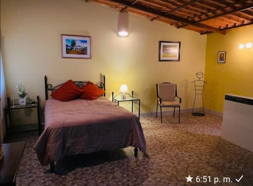 a bedroom with a bed and two tables and a chair at Albreth - Hotel Bungalows in Huaraz