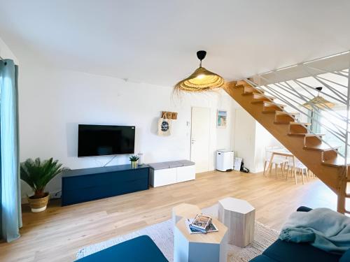 sala de estar con escalera y TV en Bord de mer, maison paisible et rénovée à Penvins, en Sarzeau