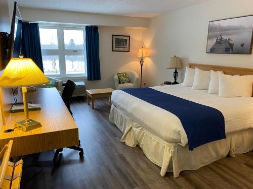 a hotel room with a large bed and a desk at Château Logue Hotel in Maniwaki