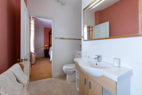 a bathroom with a sink and a toilet and a mirror at Sennen Rise in Sennen Cove