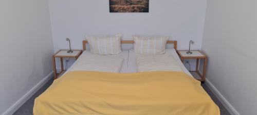 1 cama con 2 almohadas y manta amarilla en Ferienhaus Pauls Ferienhaus Pauls, Whg 06, en Norderney
