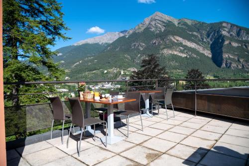 una mesa y sillas en un balcón con montañas en Résidence Château des Magnans by Nevesol, en Jausiers