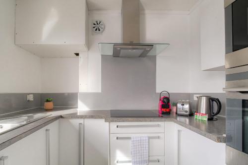 - une cuisine blanche avec des placards blancs et une cuisinière dans l'établissement Lumineux et Calme avec parking gratuit, à Villeurbanne