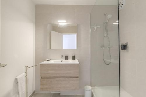 une salle de bain blanche avec un lavabo et une douche dans l'établissement Lumineux et Calme avec parking gratuit, à Villeurbanne