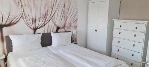 a bedroom with a bed with white sheets and a dresser at Dünenrose Seegras Nr 41 in Norderney