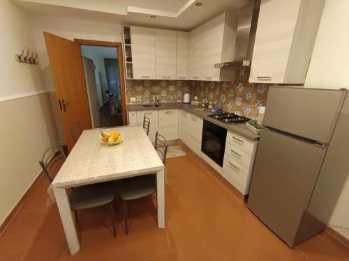 a kitchen with a table and a refrigerator at La Casetta per te in Gravina di Catania