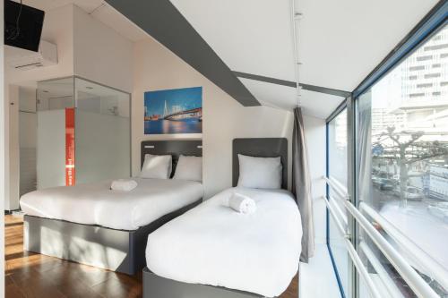 two beds in a room with a window at easyHotel Rotterdam City Centre in Rotterdam