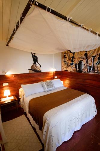 a bedroom with a bed with a canopy at MADIROKELY HOUSE Nosy Be in Ambatoloaka