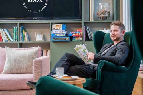 a man sitting in a chair reading a book at KOOS Hotel&Apartments - City Aparthotel in Munich