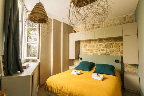 - une chambre dotée d'un lit jaune avec deux animaux rembourrés dans l'établissement Le Petit Nid - 2 personnes - Paris 3 - Terrasse, à Paris