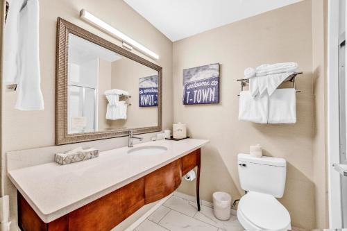a bathroom with a sink and a toilet and a mirror at Wingate by Wyndham Tuscaloosa in Tuscaloosa