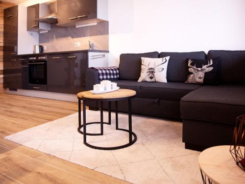 ein Wohnzimmer mit einem schwarzen Sofa und einem Tisch in der Unterkunft Apartment Les Chavonnes by Interhome in Gryon