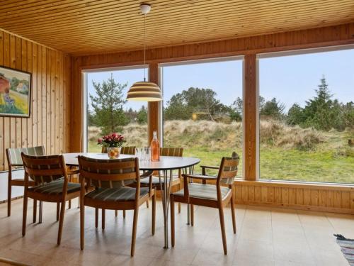 een eetkamer met een tafel en stoelen en een groot raam bij Holiday Home Swenki - all inclusive - 700m from the sea by Interhome in Saltum