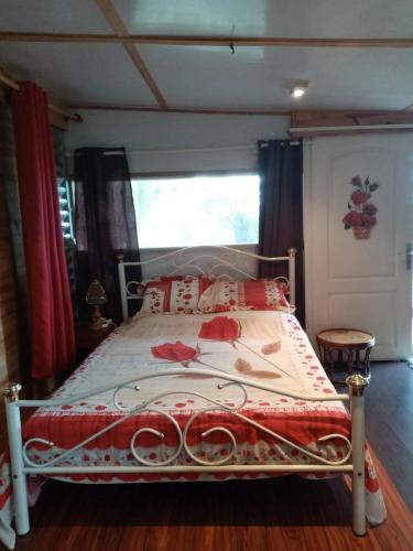 1 dormitorio con 1 cama con edredón rojo y blanco en Chalet d'une chambre avec terrasse et wifi a Les Makes, en Bellevue