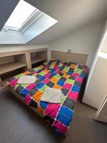 ein Schlafzimmer mit einem Bett mit einer bunten Decke darauf in der Unterkunft Zamárdi Parti Apartman in Zamárdi