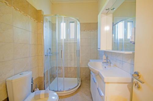 un bagno con doccia, WC e lavandino di Villa Marias Beach House by Villa Plus ad Ágios Stéfanos