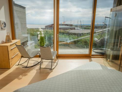 two chairs and a table in a room with a large window at Holiday Home Relax Lodge am See by Interhome in Neusiedl am See