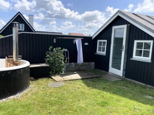 een zwart huis met een witte deur en een tuin bij Holiday Home Ofrath - all inclusive - 5m from the sea by Interhome in Otterup