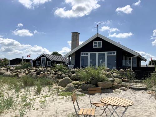 een huis op het strand met twee stoelen en een gebouw bij Holiday Home Ofrath - all inclusive - 5m from the sea by Interhome in Otterup