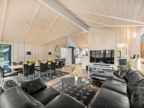 ein Wohnzimmer mit einem schwarzen Ledersofa und einem Tisch in der Unterkunft Holiday Home Jeldrik - all inclusive - 1-5km from the sea by Interhome in Blåvand