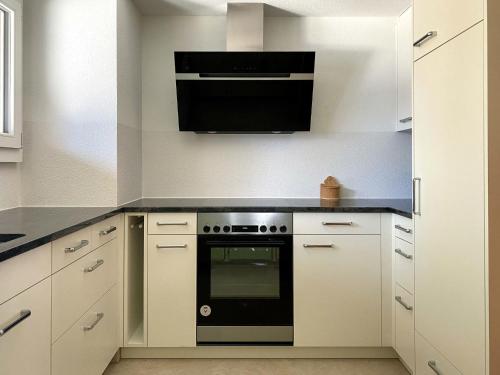 una cocina con armarios blancos y horno negro en Apartment Chalet Colette-2 by Interhome, en Grindelwald