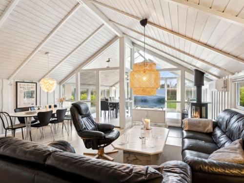 een woonkamer met lederen meubels en een eetkamer bij Holiday Home Chrisse - all inclusive - 250m from the sea by Interhome in Otterup