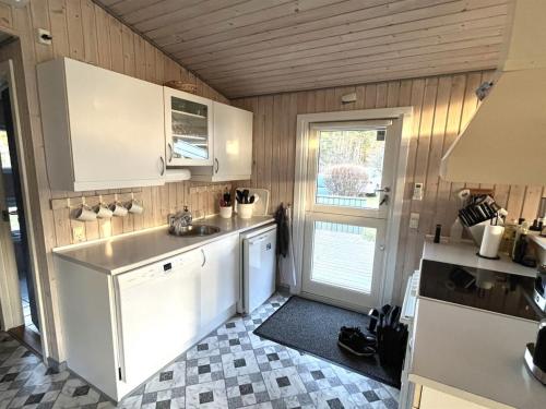 una cocina con armarios blancos y fregadero en Holiday Home Blia - all inclusive - 125m from the sea by Interhome, en Lumsås