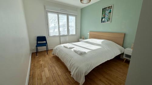 une chambre avec un lit blanc et une chaise bleue dans l'établissement Côté Sable, un balcon sur la mer - parking inclus, à Boulogne-sur-Mer