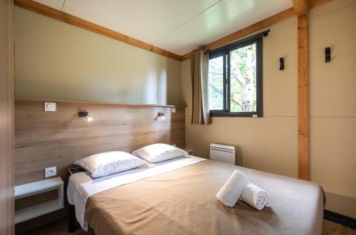 a bedroom with a large bed with two pillows at Huttopia Baie du Mont Saint Michel in Baguer-Pican