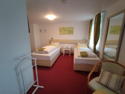 Habitación pequeña con 2 camas y silla en Room in Guest room - Pension Forelle - Doppelzimmer, en Forbach