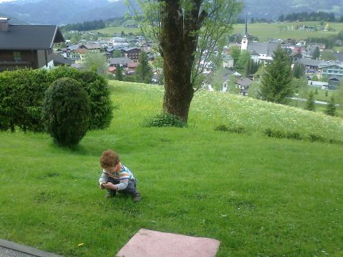 a little boy sitting in the grass on a hill at Apartment Dreier - Salzburger Land in Abtenau