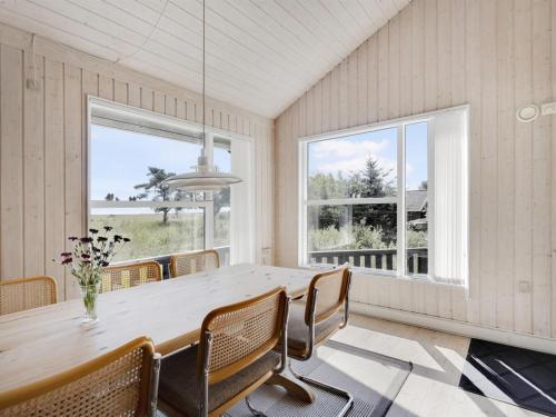 ein Esszimmer mit einem Tisch, Stühlen und Fenstern in der Unterkunft Holiday Home Griselda - all inclusive - 400m from the sea by Interhome in Hadsund
