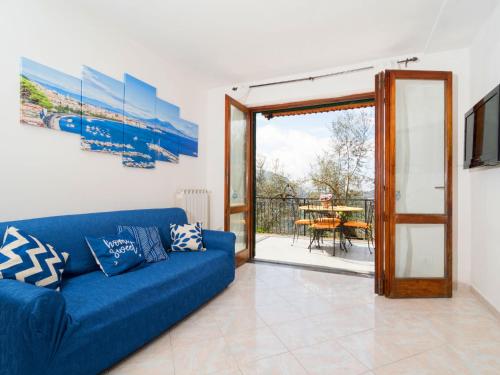 ein Wohnzimmer mit einem blauen Sofa und einer Glasschiebetür in der Unterkunft Holiday Home Candy-3 by Interhome in Nerano