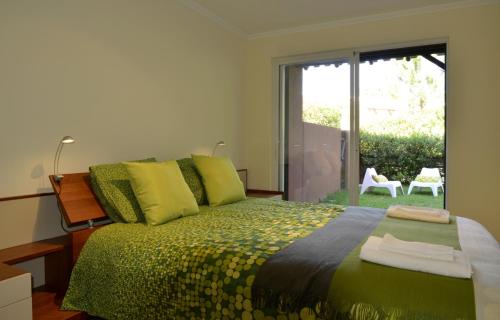 Schlafzimmer mit grünem Bett und Glasschiebetür in der Unterkunft Exciting Beach Villa in Charneca