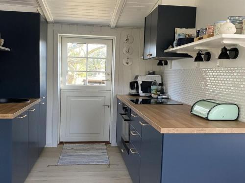 a kitchen with blue cabinets and a window and a door at Holiday Home Suoma - all inclusive - 800m from the sea by Interhome in Fanø