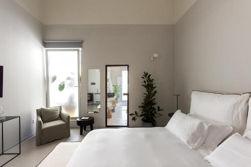 1 dormitorio con 1 cama blanca grande y 1 silla en Palazzo Console en Lecce
