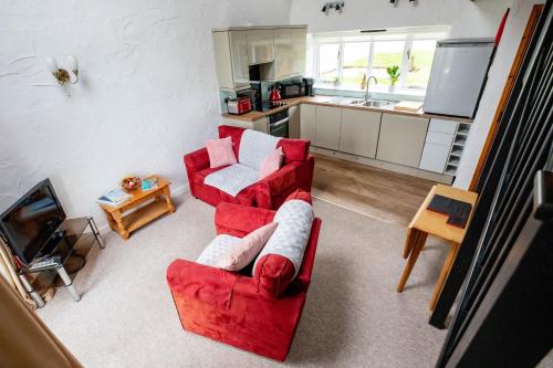 Una sala de estar con un sofá rojo y una cocina. en Treworgie Barton - Trespaddick, en Bude