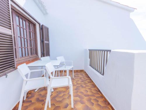 a balcony with white chairs and a table and a window at Apartment Son Bou Gardens PLUS by Interhome in Son Bou