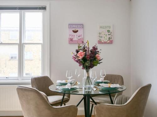 una mesa de comedor con sillas y un jarrón de flores en Charming one bedroom flat on Portobello Road en Londres