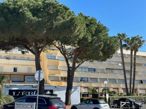 2 arbres dans un parking en face d'un bâtiment dans l'établissement Village naturiste - Port-Nature 6 - Le Phare, au Cap d'Agde