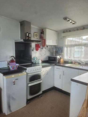 a kitchen with white cabinets and a stove top oven at Chalet 69 in Mundesley