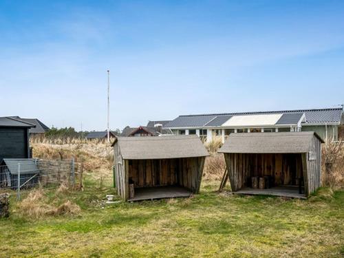 dos cabañas de madera en un campo frente a un edificio en Holiday Home Nafne - all inclusive - 1-2km from the sea by Interhome, en Hvide Sande