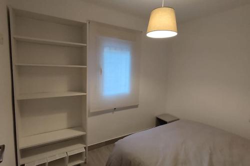 ein Schlafzimmer mit einem Bett, einem Fenster und Regalen in der Unterkunft Apartamento moderno a 1km de Granada in Granada
