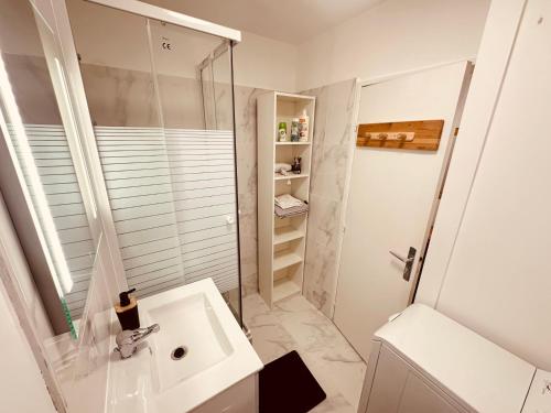 uma casa de banho branca com um chuveiro e um lavatório. em Studio Élégant à Cergy em Cergy