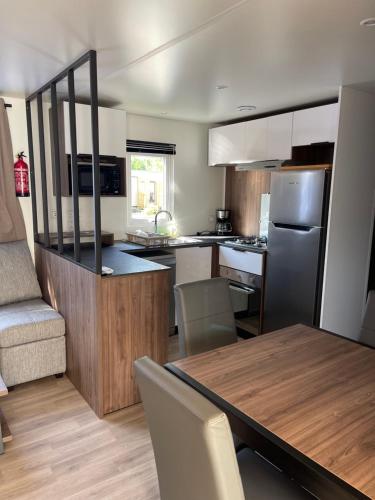 une cuisine et une salle à manger avec une table et un réfrigérateur dans l'établissement Mobil Home FI11 Camping les Viviers, à Lège-Cap-Ferret