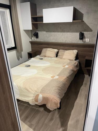 une chambre avec un grand lit avec un plancher en bois dans l'établissement Mobil Home FI11 Camping les Viviers, à Lège-Cap-Ferret