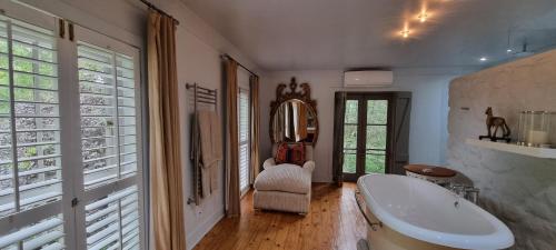a bathroom with a tub and a chair and windows at Big Sky Ranch in Colesberg